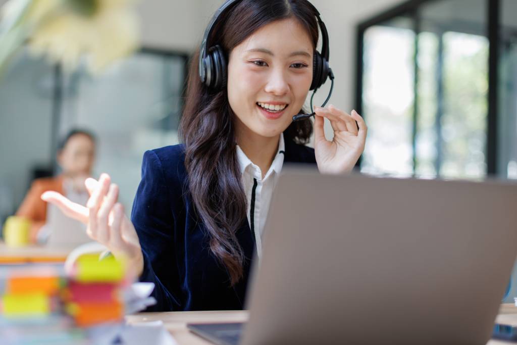 Smiling woman wearing a headset at a computer, taking a customer service call